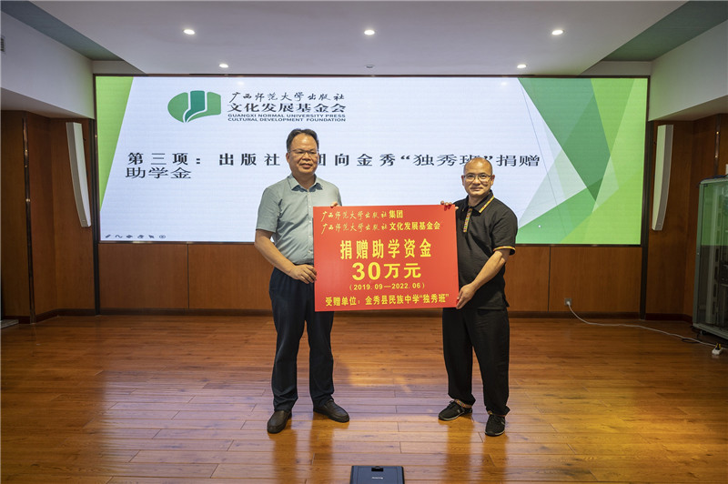 廣西師范大學(xué)出版社集團黨委書(shū)記、董事長(cháng)黃軒莊（左一）代表出版社向金秀民族中學(xué)“獨秀班”資助30萬(wàn)元（李顯楊攝）.jpg
